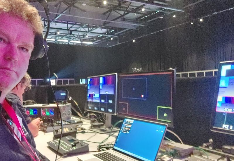 Regieplek met monitoren en beeldmenger in een congreshal